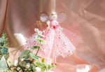 Load image into Gallery viewer, Decorative fairy figurine with pink dress and gold accents hanging among greenery.
