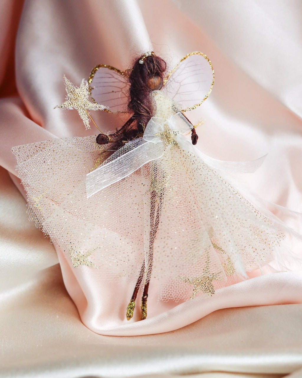 Decorative black fairy figurine on a soft pink fabric background inclusive fairy