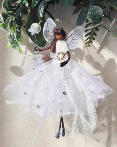 Handcrafted Snowflake Fairy wearing a white silk dress with sparkly glitter and white feathers, perfect as a Christmas tree topper. black brown south asian christmas fairy