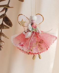 Decorative fairy ornament with pink dress and gold accents on a beige background