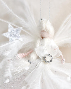 Decorative angel figure with feathers and a star on a soft beige background