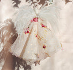 Load image into Gallery viewer, A decorative angel ornament with white feathers, a white tulle dress, and pink and gold embroidered floral details, hanging against a soft beige background with leaf shadows.
