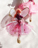 Load image into Gallery viewer, A pink fairy Christmas ornament with a glittery tutu skirt, sheer wings, and a small gold star, shown hanging against a white background with soft shadows.
