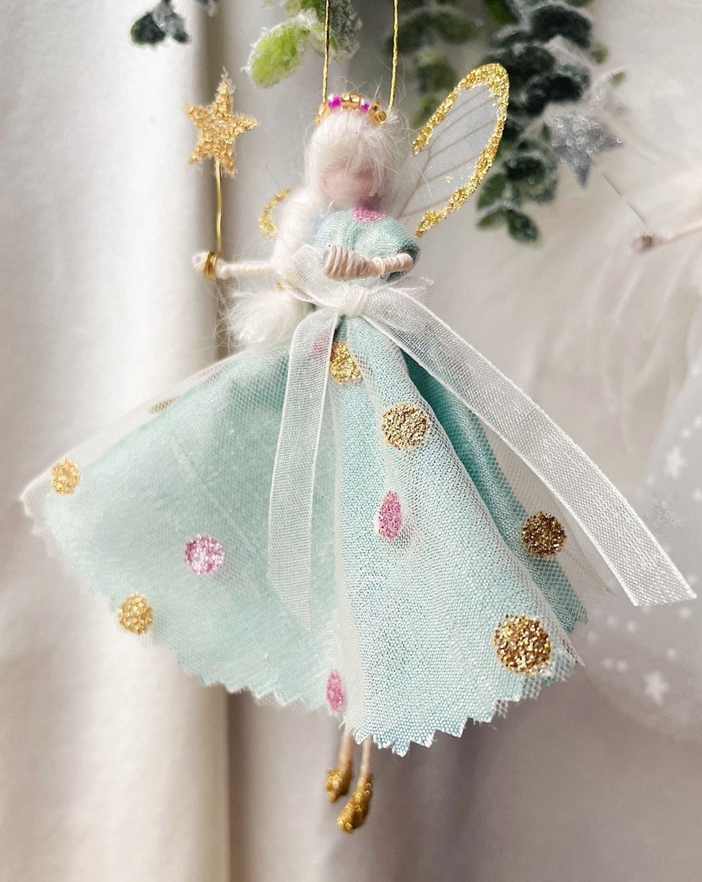 This little Fairy is dressed in a jade green Silk Dupion with an overlay of spotted tulle. She has sashed her gown at the waist with an Organza ribbon tied into a bow. Her little shoes are dipped in glitter. A beaded tiara sits upon her head, and of course, her glittered wand to grant you your wishes!
