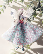 Load image into Gallery viewer, This little fairy is wearing a magical gown of Liberty print in jade and pink flowers and a sparkle tulle overskirt which gently catches the light. She has sashed her gown at the waist with an Organza ribbon and a flower trim. Her little shoes are are hand tied, and upon her head sits a little glass beaded tiara. Her delicate wings are made from silk Organza and of course, her glittered wand is there to grant your wishes!
