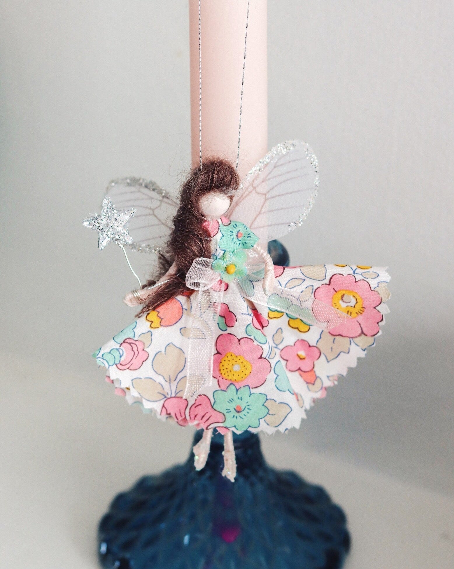 This little fairy is dressed in a Liberty print fabric. She has sashed her gown at the waist with a ivory Organza ribbon and a little rose trim. Her little shoes are dipped in glitter. She has delicate wings made from silk Organza and of course, her glittered wand that brings you magic!