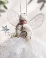 Load image into Gallery viewer, A fairy Christmas ornament with translucent wings, a white tulle dress with silver glitter accents, and a small silver star wand, photographed in soft natural light.
