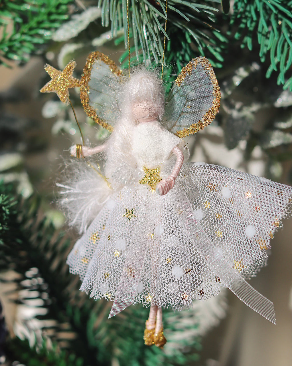 small fairy decoration hanging on the christmas tree in white and gold spotty dress
