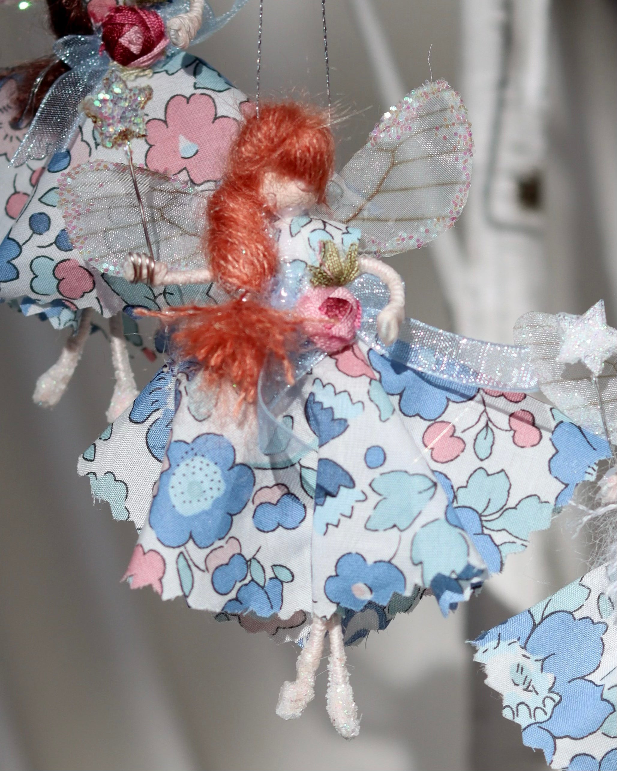 This little fairy is dressed in the “Betsy” Liberty print fabric. She has sashed her gown at the waist with a pale pink Organza ribbon and a little rose trim. Her little shoes are dipped in glitter. Her delicate wings are made from silk Organza and of course, her glittered wand