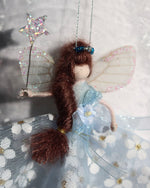 Load image into Gallery viewer, Dressed in a pale blue sparkly tulle with white flowers. She has sashed her gown at the waist with a pale blue Organza ribbon and a velvet forget-me-knot. Her little shoes are dipped in glitter, and upon her head sits a blue glass tiara. Her delicate wings are made from silk Organza and of course, her glittered wand that brings you never-ending memories!
