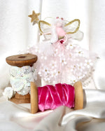 Load image into Gallery viewer, Dressed in a pale pink sparkly tulle with white flowers. She has sashed her gown at the waist with a pale pink Organza ribbon and a pink embroidered rose. Her little shoes are dipped in glitter, and upon her head sits a glass tiara. Her delicate wings are made from silk Organza and of course, her glittered wand that brings you never-ending memories!
